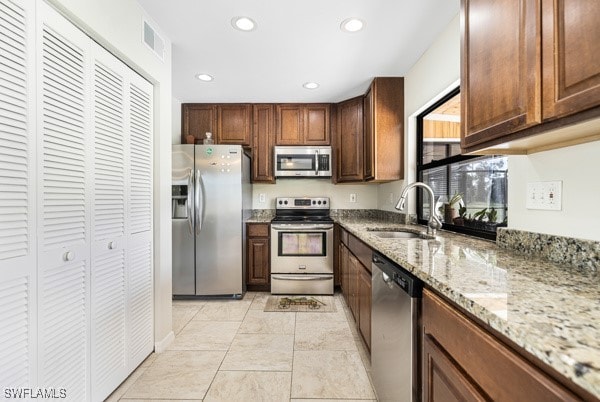 kitchen with light stone countertops, appliances with stainless steel finishes, and sink