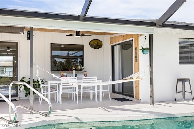 view of swimming pool featuring a patio area, glass enclosure, and ceiling fan