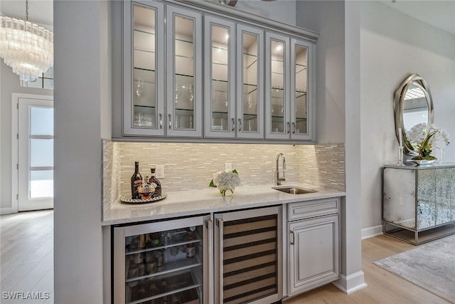 bar featuring beverage cooler, light hardwood / wood-style flooring, and sink