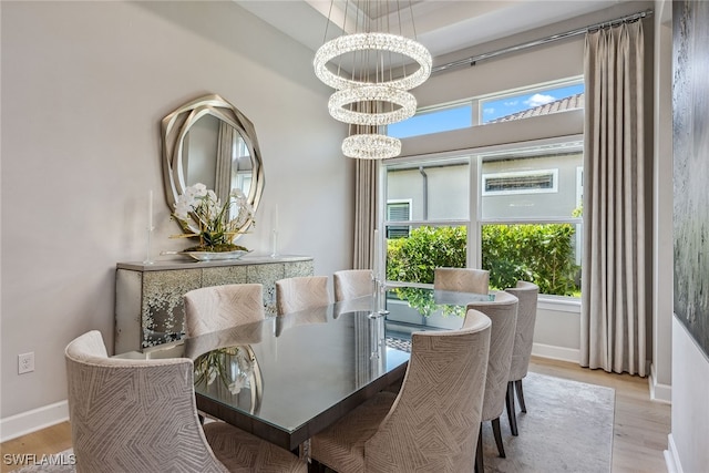 dining area with light hardwood / wood-style flooring, a wealth of natural light, and an inviting chandelier