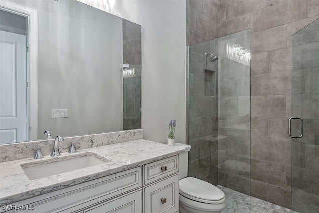 bathroom with a shower with shower door, vanity, and toilet