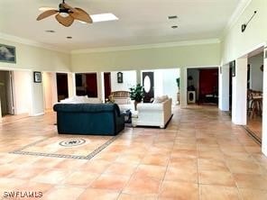 tiled living room with ornamental molding, a towering ceiling, and ceiling fan