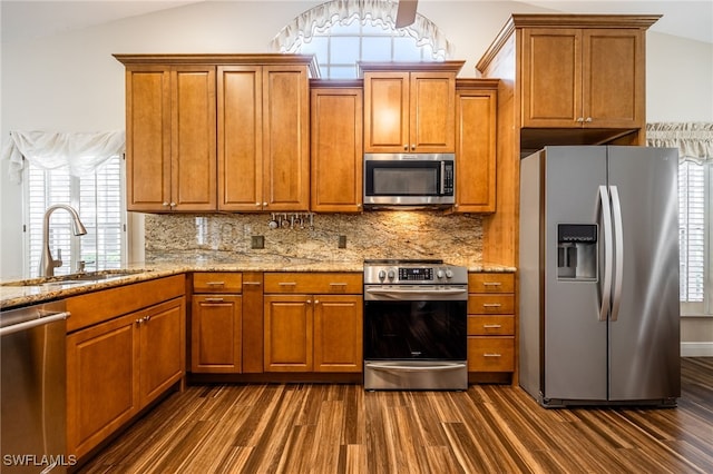 kitchen featuring dark wood-style floors, stainless steel appliances, tasteful backsplash, vaulted ceiling, and a sink