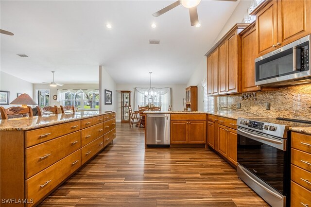 kitchen with stainless steel appliances, brown cabinetry, decorative light fixtures, and a peninsula