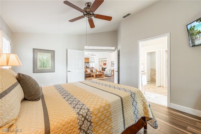 bedroom featuring ceiling fan, wood finished floors, visible vents, baseboards, and vaulted ceiling