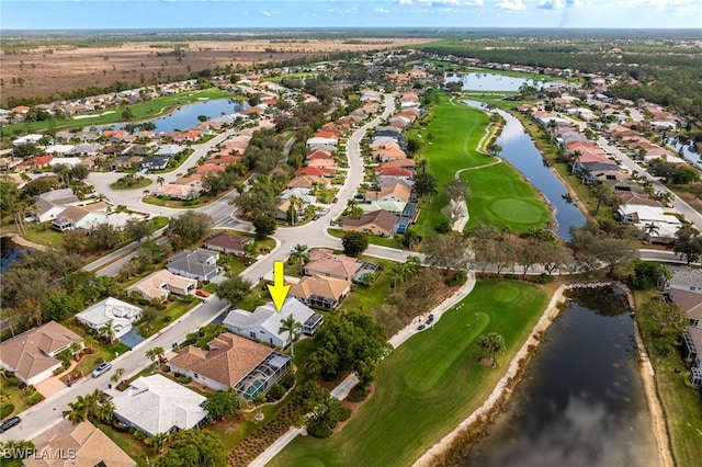 drone / aerial view featuring golf course view, a water view, and a residential view