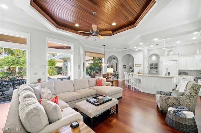 living room featuring wooden ceiling, dark hardwood / wood-style floors, ceiling fan, ornamental molding, and a tray ceiling