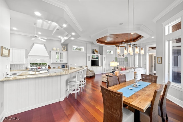 dining area featuring ceiling fan, dark hardwood / wood-style flooring, plenty of natural light, a tray ceiling, and ornamental molding