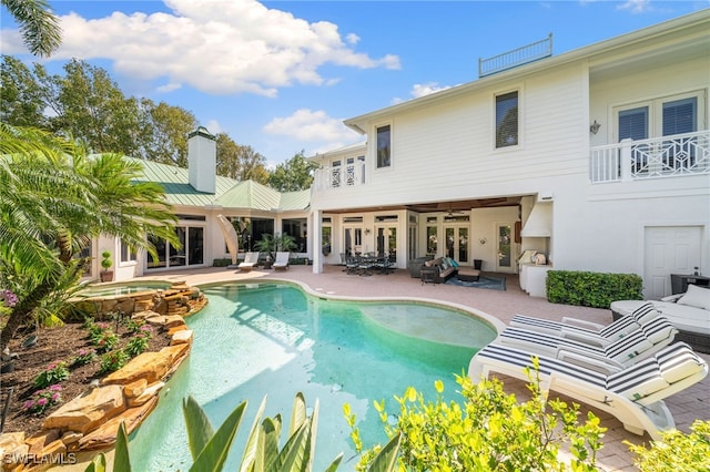 back of house featuring a pool with hot tub, a patio area, a balcony, and french doors