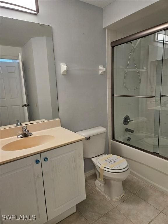 full bathroom featuring shower / bath combination with glass door, tile patterned floors, vanity, and toilet