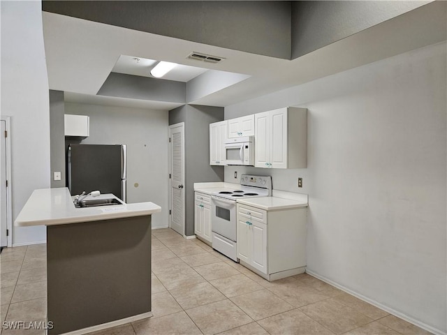 kitchen featuring white appliances, white cabinets, visible vents, light tile patterned flooring, and a sink