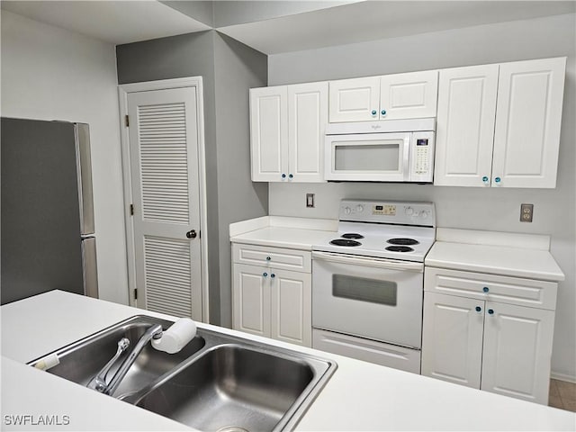 kitchen with tile patterned flooring, white cabinetry, white appliances, and sink