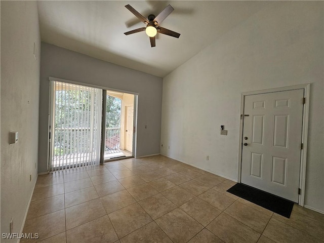 empty room featuring ceiling fan, light tile patterned floors, and vaulted ceiling