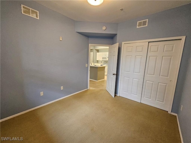 unfurnished bedroom with light colored carpet and a closet