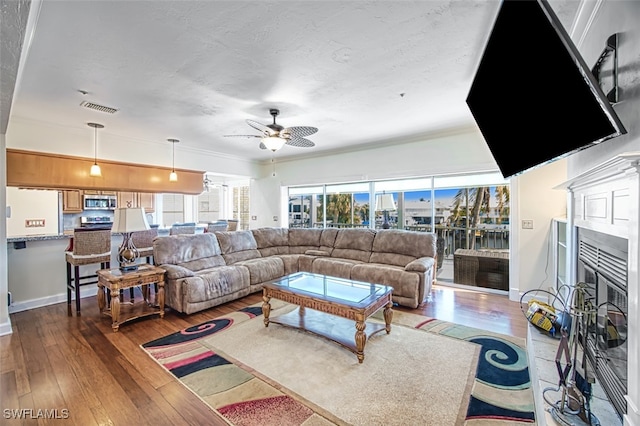 living room featuring ceiling fan, wood-type flooring, and ornamental molding