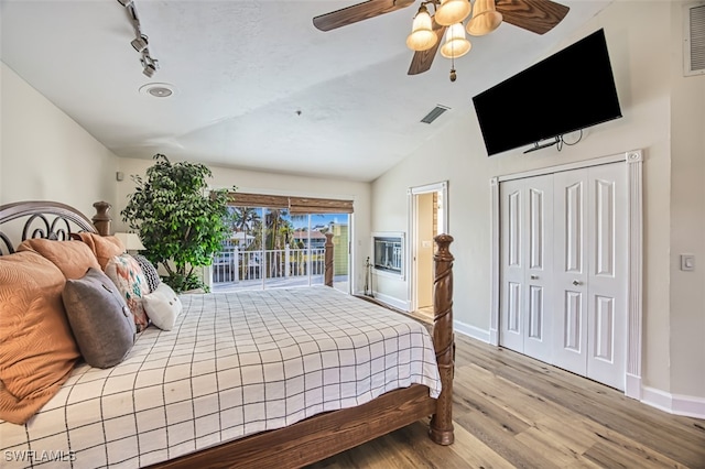 bedroom with access to exterior, light wood-type flooring, vaulted ceiling, ceiling fan, and a closet