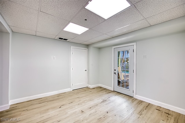 spare room featuring a paneled ceiling and light hardwood / wood-style flooring