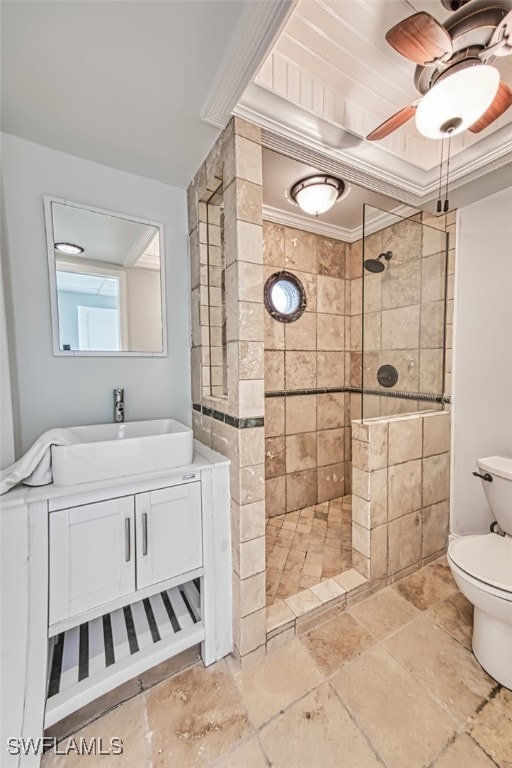 bathroom featuring toilet, vanity, ornamental molding, and tiled shower