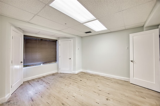 spare room with a drop ceiling and light hardwood / wood-style flooring