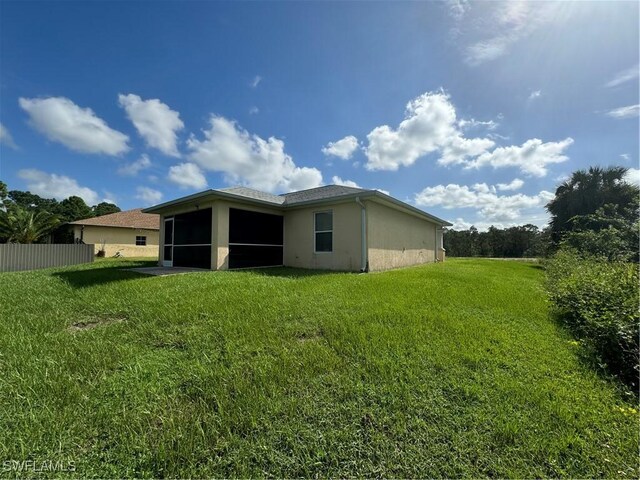 rear view of property with a lawn and a sunroom