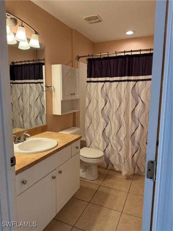 bathroom featuring curtained shower, tile patterned flooring, vanity, and toilet