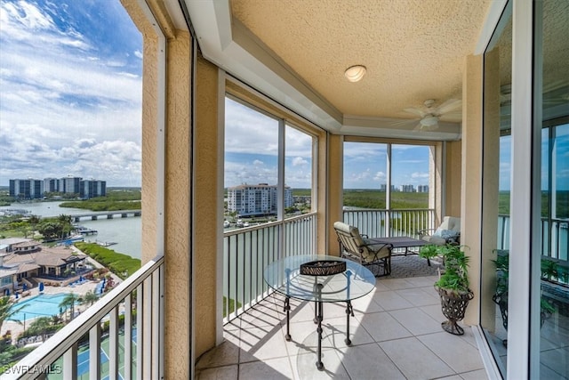 sunroom featuring a water view and ceiling fan