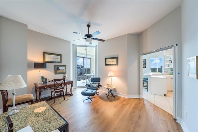 sitting room with light wood-type flooring, ceiling fan, and sink