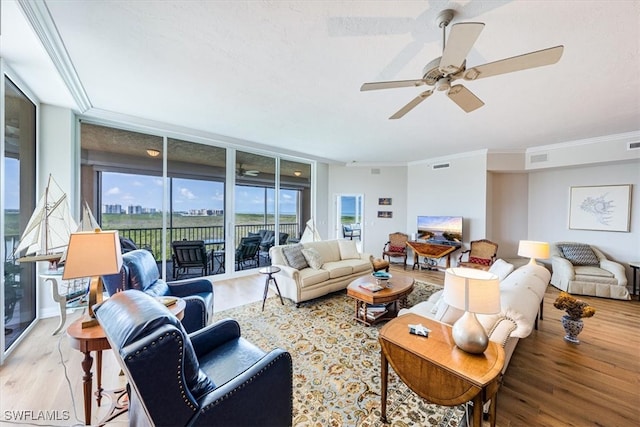 living room with light wood-type flooring, expansive windows, ornamental molding, and ceiling fan