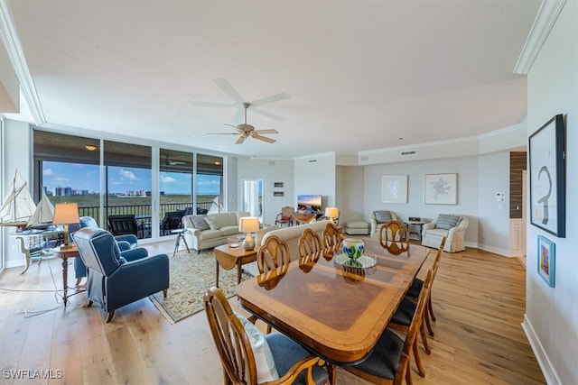 dining room with ceiling fan, a wall of windows, ornamental molding, and light hardwood / wood-style flooring