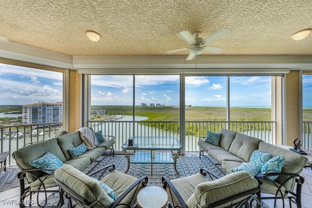 sunroom / solarium featuring ceiling fan and a water view