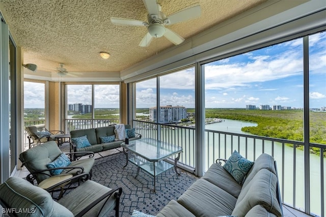 sunroom featuring ceiling fan, plenty of natural light, and a water view