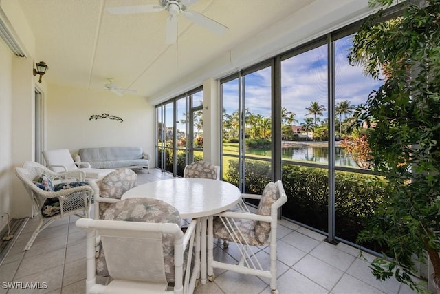 sunroom / solarium with ceiling fan and a water view