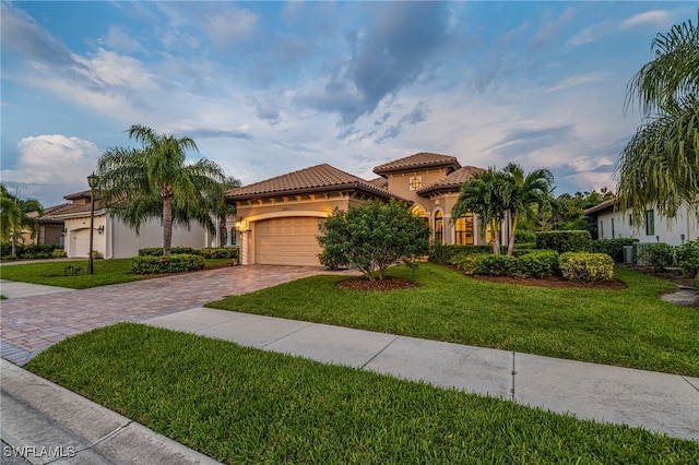 mediterranean / spanish home featuring a garage and a front lawn