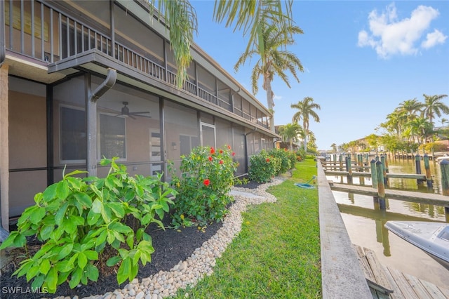 view of yard featuring ceiling fan, a balcony, and a sunroom