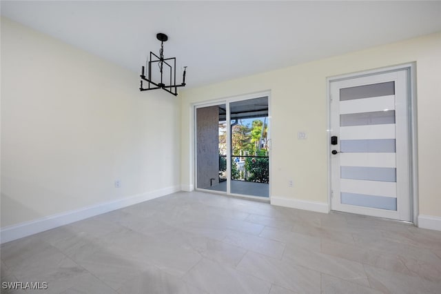 unfurnished room featuring a chandelier