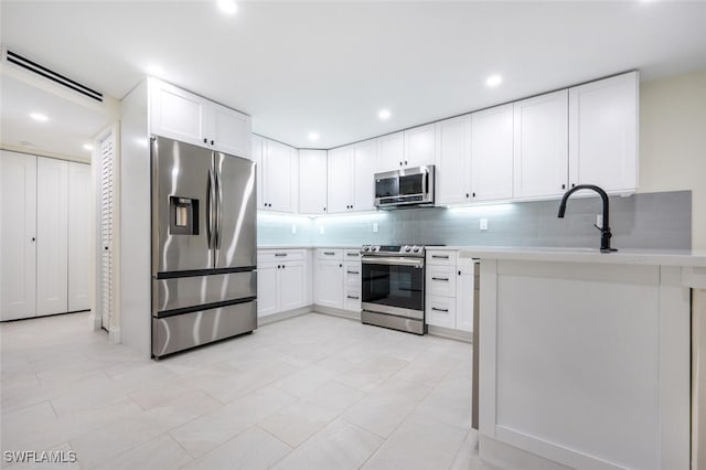 kitchen featuring tasteful backsplash, sink, white cabinets, appliances with stainless steel finishes, and light tile patterned floors