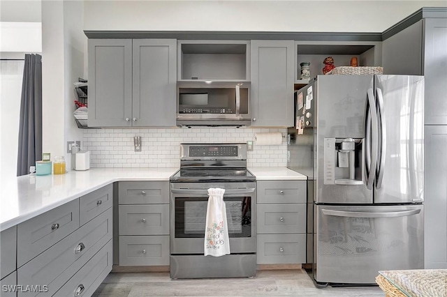 kitchen with gray cabinetry, decorative backsplash, and stainless steel appliances