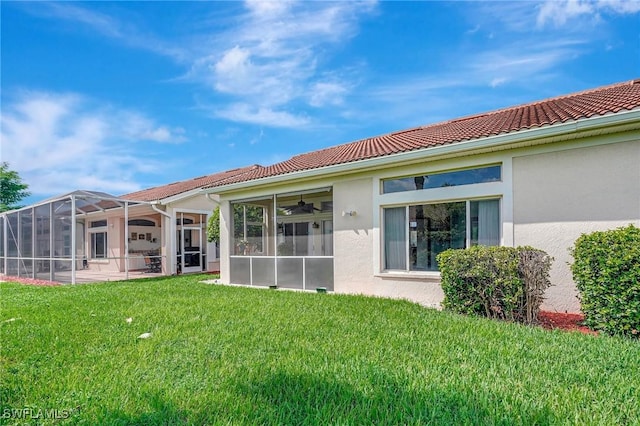 rear view of property featuring a yard and glass enclosure