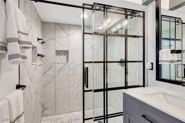 bathroom with a tile shower and vanity