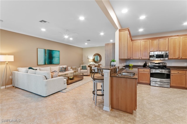 kitchen featuring kitchen peninsula, ceiling fan, a kitchen breakfast bar, sink, and stainless steel appliances