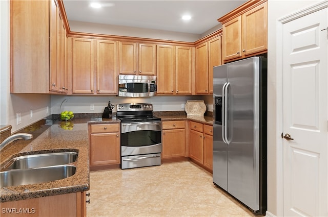 kitchen featuring dark stone countertops, appliances with stainless steel finishes, and sink