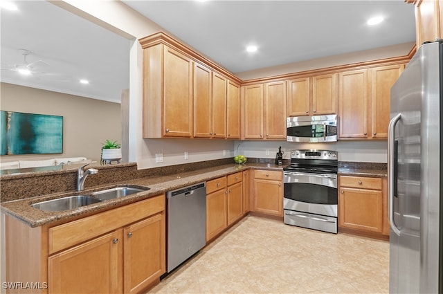 kitchen featuring dark stone countertops, crown molding, appliances with stainless steel finishes, and sink