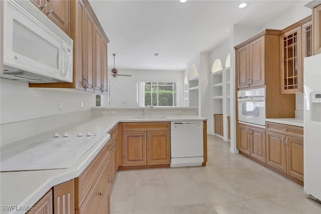 kitchen with kitchen peninsula, ceiling fan, light tile patterned flooring, sink, and white appliances