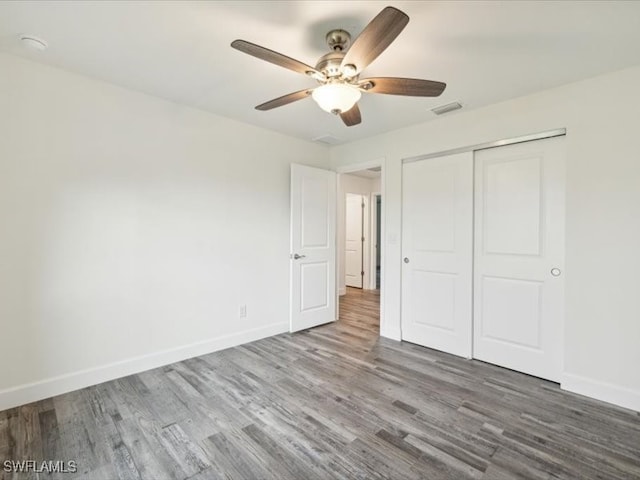 unfurnished bedroom featuring ceiling fan, hardwood / wood-style flooring, and a closet