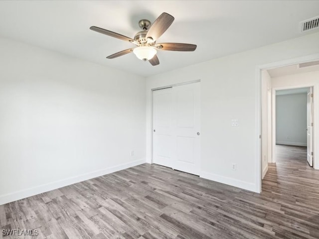 unfurnished bedroom featuring ceiling fan, a closet, and wood-type flooring