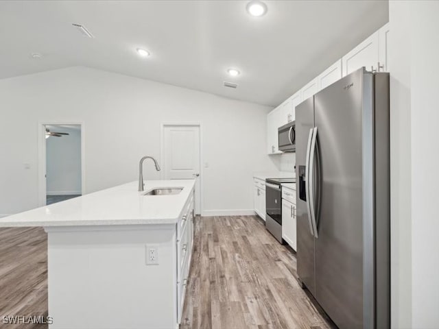 kitchen featuring stainless steel appliances, lofted ceiling, white cabinets, and an island with sink