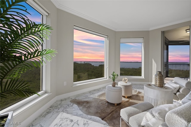 living area with a wealth of natural light, crown molding, and a water view