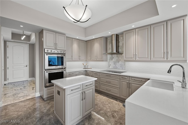 kitchen with wall chimney range hood, sink, decorative light fixtures, a center island, and stainless steel double oven