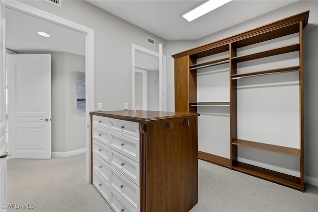 walk in closet with light colored carpet