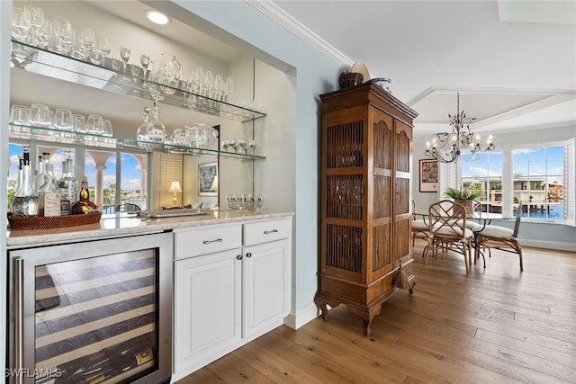 bar featuring ornamental molding, white cabinetry, hardwood / wood-style flooring, and beverage cooler